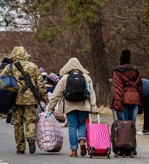 Uzhhorod, Ukraine - February 26, 2022: Ukrainian border guard helps to carry bags to refugees leaving the country through the Ukrainian-Slovak border.