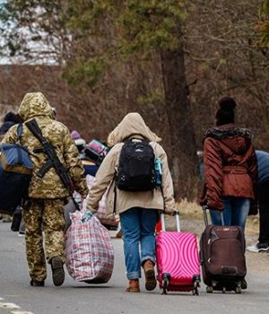 Uzhhorod, Ukraine - February 26, 2022: Ukrainian border guard helps to carry bags to refugees leaving the country through the Ukrainian-Slovak border.